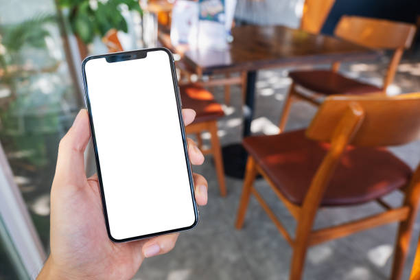 istock a hand holding and showing black mobile phone with blank white screen in cafe 1190965490