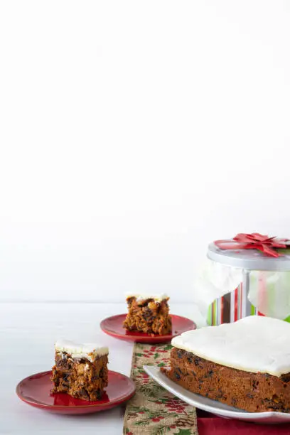 Rich Fruit Christmas Cake on Table with Present on light background with copy space Vertical