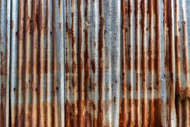 Photo of Rusted galvanized iron plate, red stain on old metal sheet wall texture.