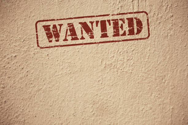 Close-up of Wanted Sign Stamped on Brown Wall Background.