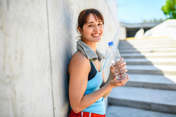 istock Smiling Female Runner with Water Bottle Resting in Shade 1190984684