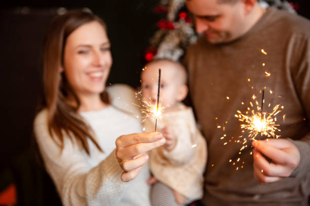 happy smiling caucasian family with newborn baby with sparklers. - new year people family offspring imagens e fotografias de stock