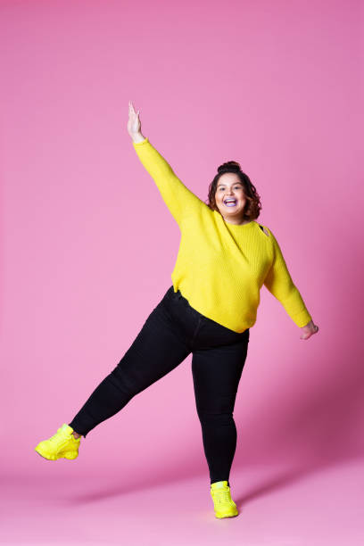 Cheerful plus size model in casual clothes, fat woman in black jeans and yellow jumper on pink background Cheerful plus size model in casual clothes, fat woman in black jeans and yellow jumper on pink background, body positive concept, full-length portrait huge black woman pictures stock pictures, royalty-free photos & images