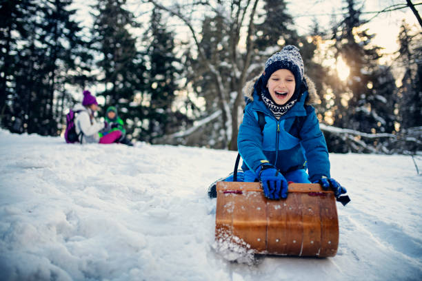 niño pequeño disfrutando toboganing en el día de invierno - deslizarse en trineo fotografías e imágenes de stock