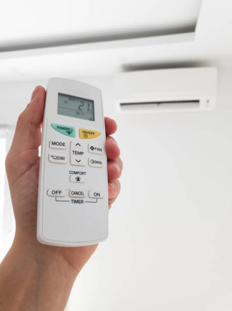 istock Modern air conditioner unit with a hand holding a remote. 1190995355