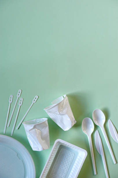 istock Plastic cups, spoons, knives, stirrers, plate and box on green 1190998964