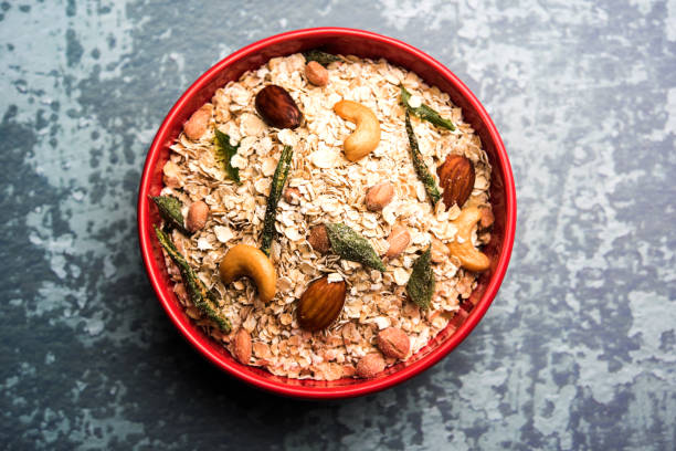 Oats Chivda / Chiwda is a healthy indian recipe with added chilli, peanuts, cashew, almond and curry leaf for flavour. Selective focus stock photo