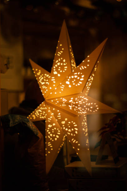 istock Big orange illuminated decorative Christmas star perforated shinning inside dimly lit room 2019 1191007278