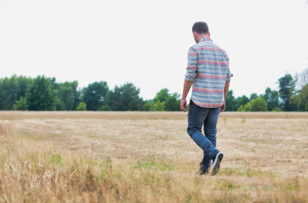 istock Rear view of Man walking alone in field 1191009975