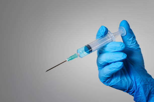 Hand in a blue glove holding a syringe. stock photo