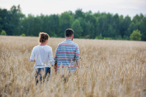 istock Young couple walking while holding hands in wheat field 1191014387
