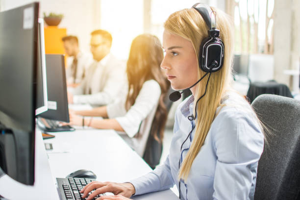 istock Blond businesswoman or helpline operator with headset using computer at office 1191014715