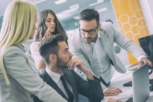 istock Group of young confident business people analyzing data using laptop during a meeting in the office 1191015304