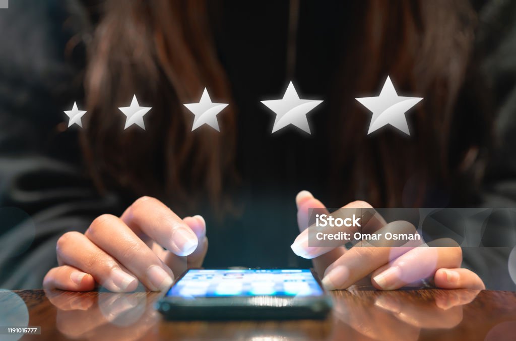 Hands of young woman completing customer satisfaction survey on electronic mobile smartphone with five silver graphic stars Woman filling out 5 star silver customer service feedback survey by email on smartphone device after hotel guest experience - Company satisfaction rating, retention and quality of service concepts Customer Experience Stock Photo