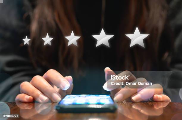 Hands Of Young Woman Completing Customer Satisfaction Survey On Electronic Mobile Smartphone With Five Silver Graphic Stars Stock Photo - Download Image Now