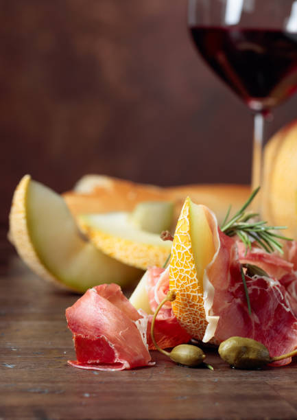 istock Prosciutto with melon, capers and rosemary on a old wooden table. 1191019715