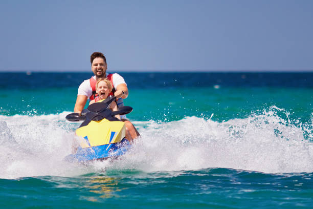 happy, excited family, father and son having fun on jet ski at summer vacation happy, excited family, father and son having fun on jet ski at summer vacation racing boat photos stock pictures, royalty-free photos & images