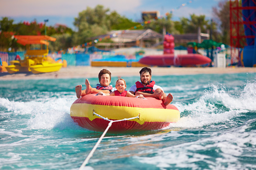 excited friends, family having fun, riding on water tube during summer vacation