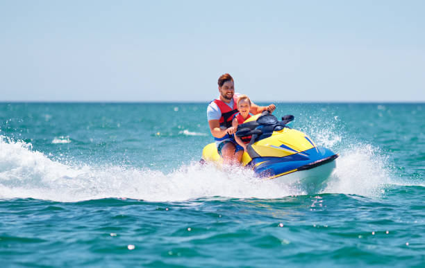 famille heureuse et excitée, père et fils ayant l'amusement sur le jet ski aux vacances d'été - ski boat photos et images de collection