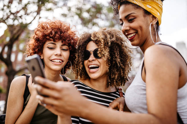 istock Three girl friends using phone in city 1191028442