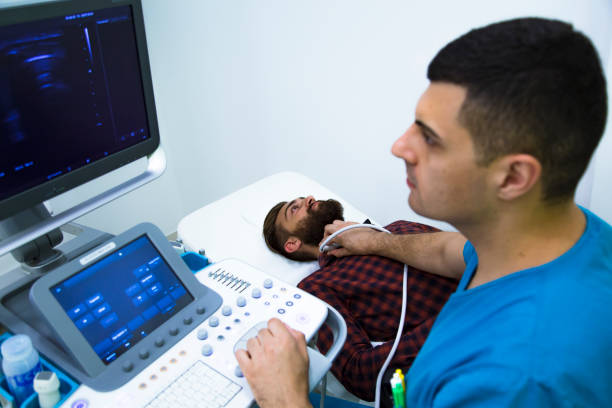 Doctor examining thyroid gland with ultrasound machine in hospital stock photo