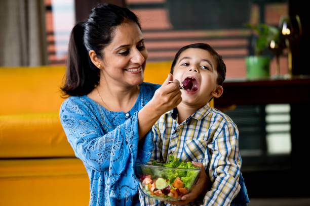 istock Happy mother feeding fruit salad to son 1191031851