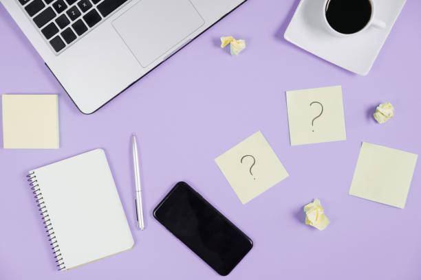 istock Question mark on sticky notes, notebook, laptop, cup coffee, phone, pen on violet background. FAQ concept. Working with clients. Troubles in work. Flat lay, top view, copy space 1191037040