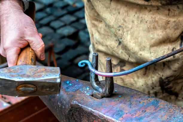 Blacksmith is processing a hot metal object at anvil in a workshop Blacksmith is processing a hot metal object at anvil in a workshop bellows stock pictures, royalty-free photos & images