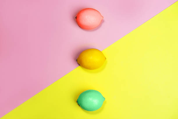 Creative pattern made of lemons on bright yellow and pastel pink background.