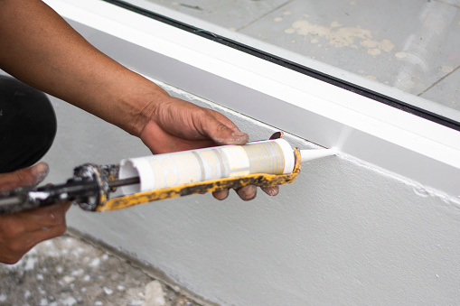 Reparador a mano instalando las ventanas con silicona pistola. Closeup photo