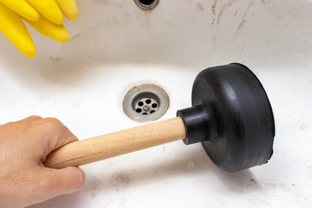 égout bloqué, cuvette de lavage obstruée, drain de bassin, gants en caoutchouc jaunes et une main retenant un piston dans la salle de bains à la maison, concept de plomberie et d'entretien - wash bowl photos et images de collection