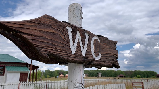 An outdoor wooden arrow signboard WC, public restroom sign in a countryside park