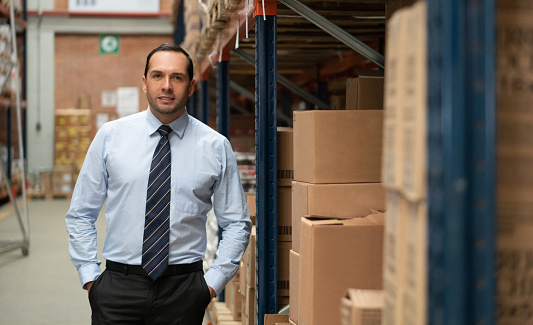 Latin American business manager working at a warehouse and looking at the camera