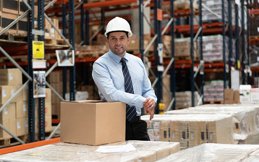 Portrait of a successful business owner working at a warehouse and looking at the camera smiling