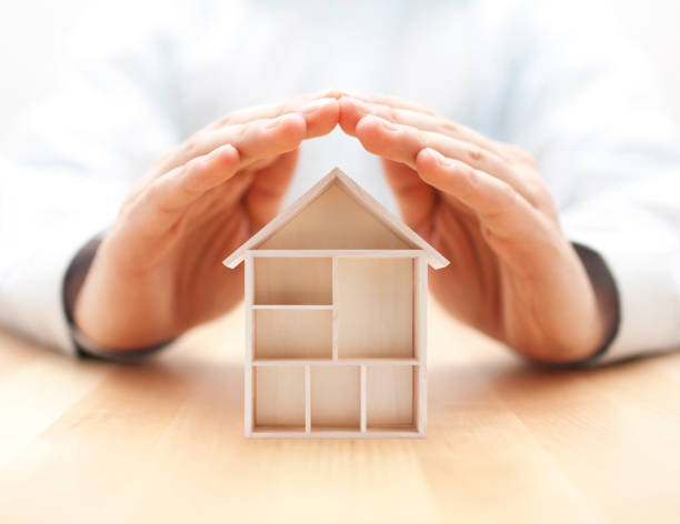 istock Wooden house protected by hands 1191051855