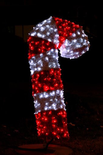 Christmas night lights simulating shape of red white Xmas candy cane stick. Street city New Year and Christmas decorations, string rice lights bulbs. Ornaments to christmas celebration, holiday scene.