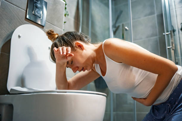 Young caucasian woman in toilet Young caucasian woman in toilet - pregnant, drunk or illness concept. Young dark-haired woman vomiting in toilet. Woman getting sick and vomiting over a toilet bowl kneeling down with her arms resting on the seat food poisoning photos stock pictures, royalty-free photos & images