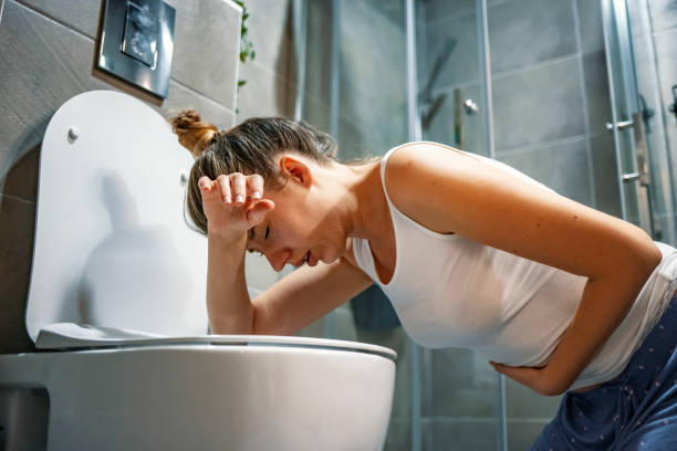 Young caucasian woman in toilet Young caucasian woman in toilet - pregnant, drunk or illness concept. Young dark-haired woman vomiting in toilet. Woman getting sick and vomiting over a toilet bowl kneeling down with her arms resting on the seat puke stock pictures, royalty-free photos & images