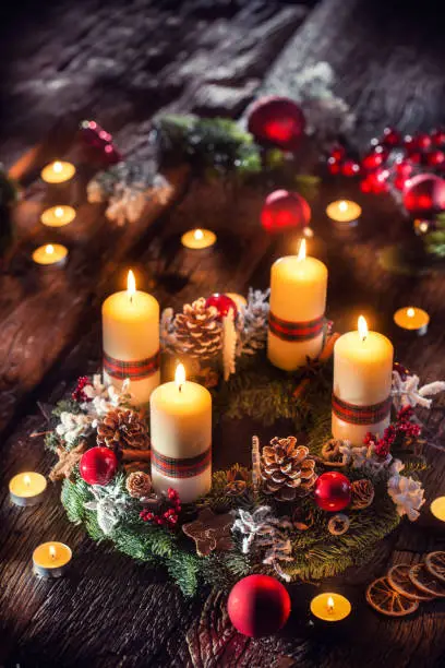 Advent wreath with four white burning candles christmas ball and decorations on a wooden background with festive atmosphere.