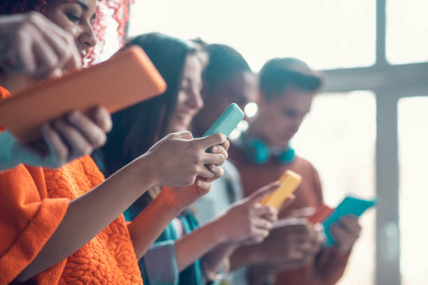 étudiants retenant les smartphones colorés tout en ayant la rupture de l'étude - telephone window mobile phone addiction photos et images de collection