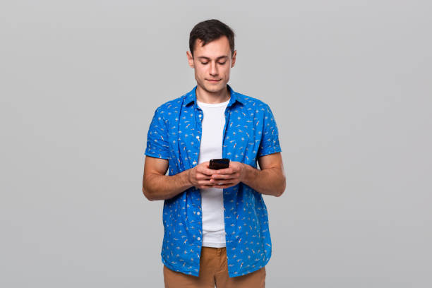 istock Handsome young man checking notifications on a smartphone isolated over grey background. 1191065698