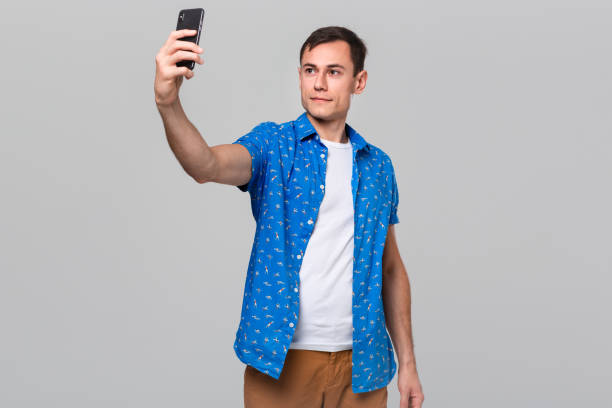 istock Handsome man making selfie with a mobile phone isolated over grey background. 1191065707