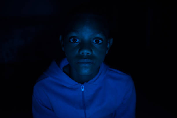 Portrait of young boy in dark with blue light reflecting