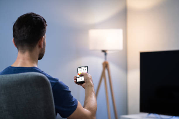 istock Human Hand Adjusting Electric Light Through Mobile Phone 1191071304