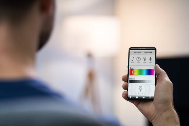 istock Human Hand Adjusting Electric Light Through Mobile Phone 1191071307