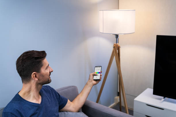 istock Human Hand Adjusting Electric Light Through Mobile Phone 1191071309