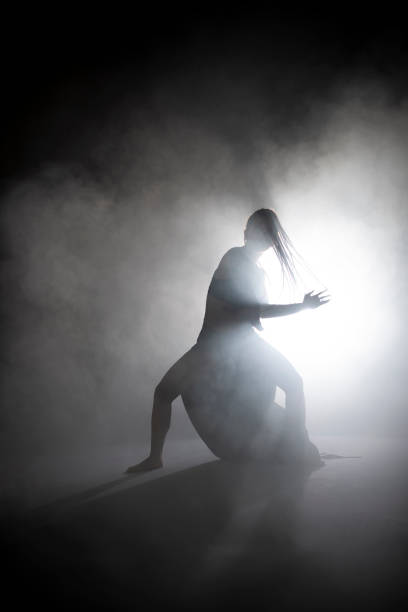 istock Silhouette dancer woman performing dance figures in fog. 1191072073