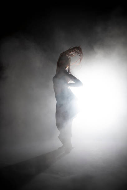 istock Silhouette dancer woman performing dance figures in fog. 1191072076