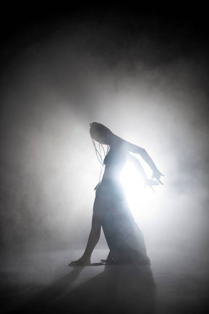 istock Silhouette dancer woman performing dance figures in fog. 1191072082