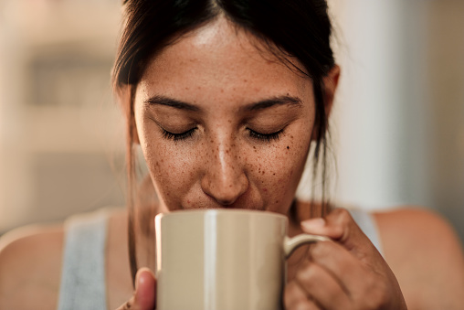 Shot of a young woman enjoying a cup of coffee at home